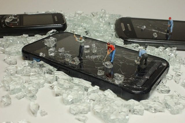 rozbitý displej na telefonu – malé figurky, které ho rozbíjejí